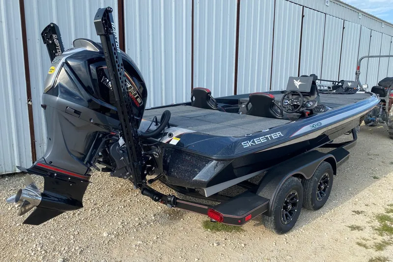 Slide: The Image of 2026 Skeeter ZXE21 boat with powerful outboard motor, parked beside a metal building. - 5