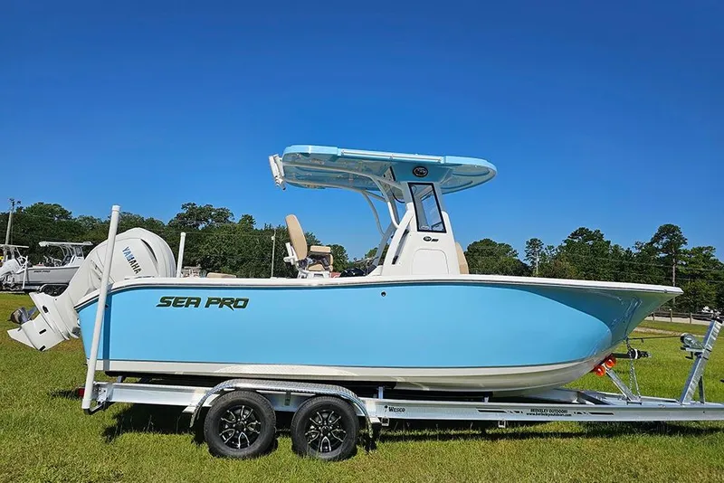 The Image of 2025 Sea Pro 242 Center Console boat on trailer, blue hull, sunny day. - 1