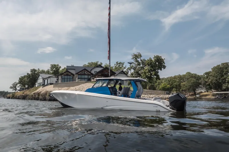 Slide: The Image of 2026 Fountain 43 SCX boat on a scenic lake near modern waterfront homes. - 34