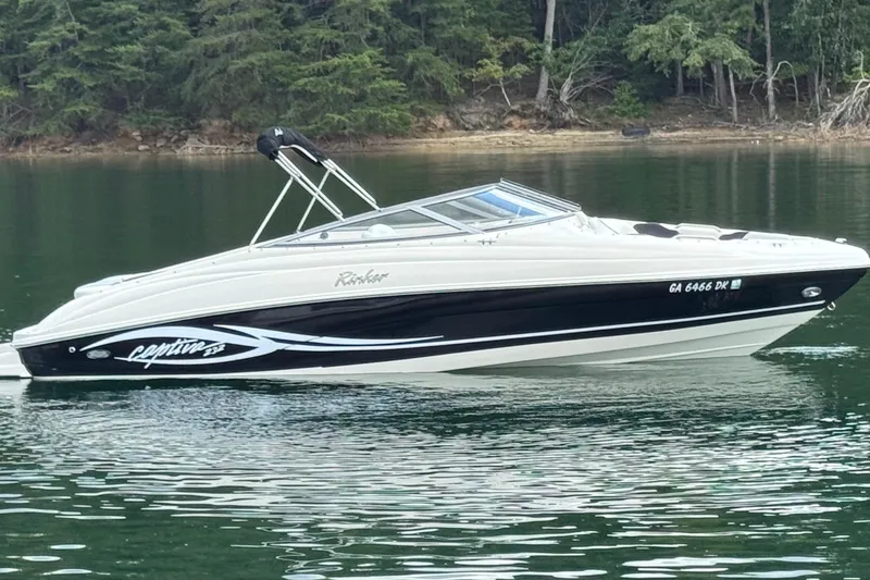 Slide: The Image of 2005 Rinker 232 Captiva Bowrider on calm lake with forested background. - 10