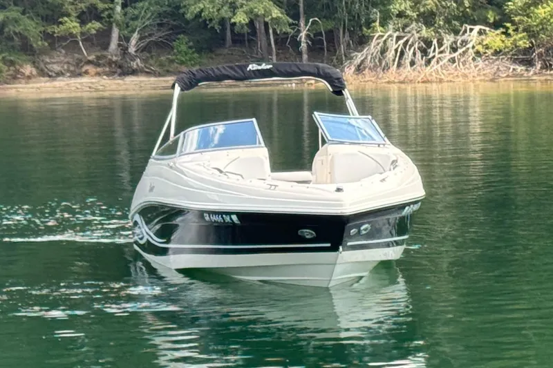 Slide: The Image of 2005 Rinker 232 Captiva Bowrider on calm lake with forested shoreline. - 12