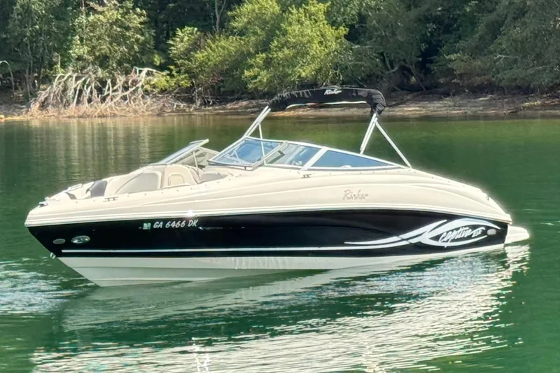 Slide: The Image of 2005 Rinker 232 Captiva Bowrider on calm lake with lush green shoreline. - 14