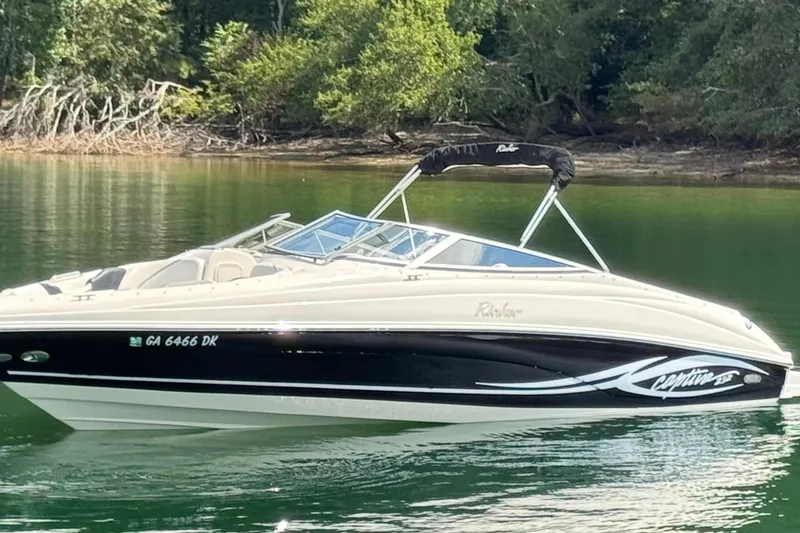 Slide: The Image of 2005 Rinker 232 Captiva Bowrider on calm water, surrounded by lush greenery. - 16