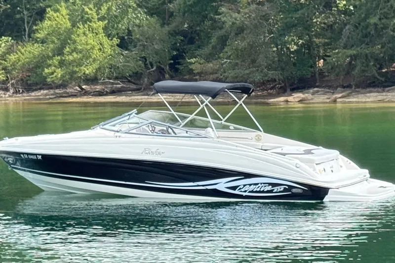 Slide: The Image of 2005 Rinker 232 Captiva Bowrider on calm lake with lush green shoreline. - 17