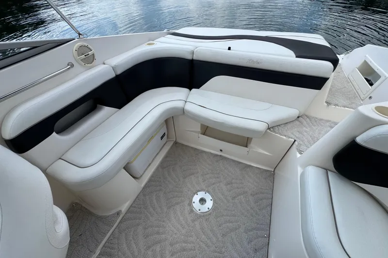 Slide: The Image of 2005 Rinker 232 Captiva Bowrider interior with white and black seating, near water. - 22