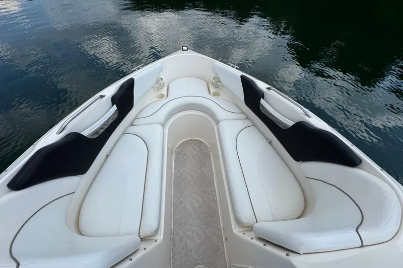 Slide: The Image of 2005 Rinker 232 Captiva Bowrider interior with white seating, on calm water. - 24