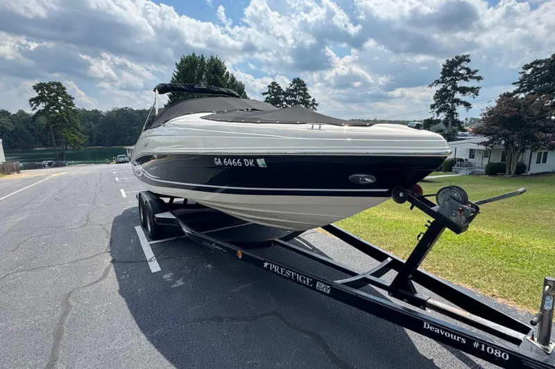 Slide: The Image of 2005 Rinker 232 Captiva Bowrider on trailer, parked near a lake under cloudy sky. - 25