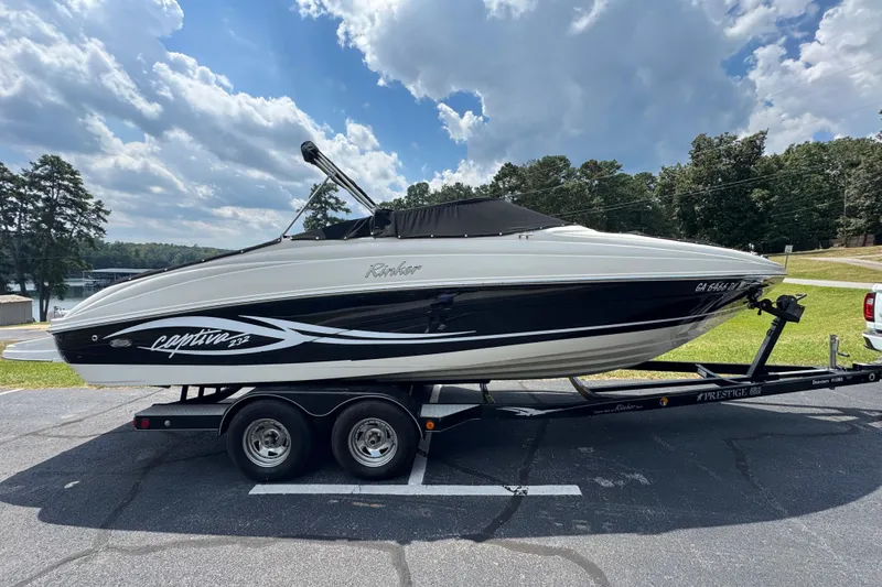 Slide: The Image of 2005 Rinker 232 Captiva Bowrider on trailer, parked outdoors under a partly cloudy sky. - 27