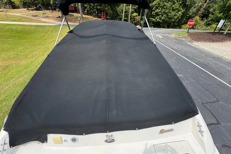 Slide: The Image of 2005 Rinker 232 Captiva Bowrider with black cover, parked on pavement near grassy area. - 29