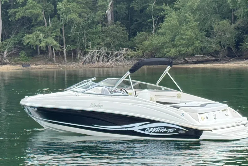 Slide: The Image of 2005 Rinker 232 Captiva Bowrider on a serene lake with forested shoreline. - 6
