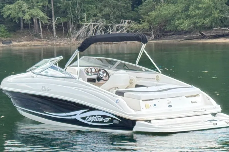 Slide: The Image of 2005 Rinker 232 Captiva Bowrider on calm lake with forested shoreline. - 7