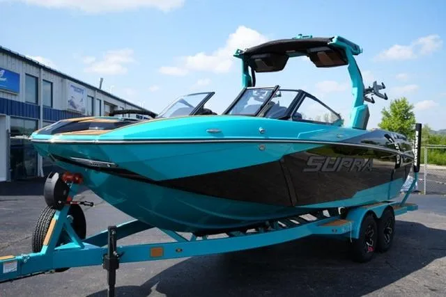 The Image of 2026 Supra SL boat in vibrant turquoise on a trailer, parked outdoors. - 1