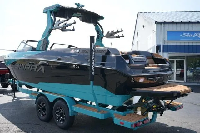 Slide: The Image of 2026 Supra SL boat on trailer, black and teal design, parked outside dealership. - 5
