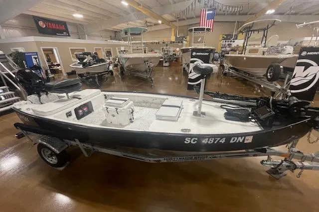 Slide: The Image of 2020 Santee 160TS boat in showroom, featuring motor and equipment, with American flag in background. - 8