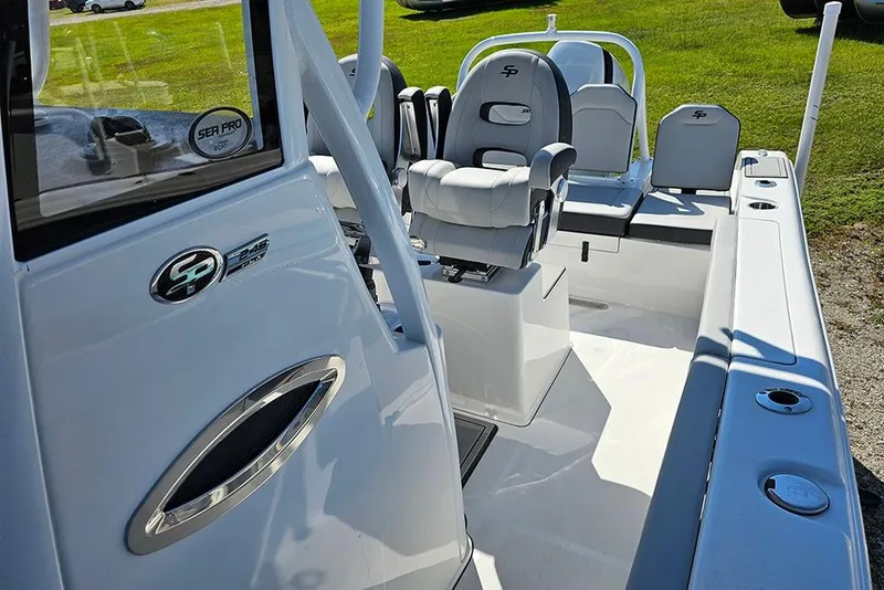 Slide: The Image of 2026 Sea Pro 245 Sandbar boat interior with seating and console, parked on grass. - 10