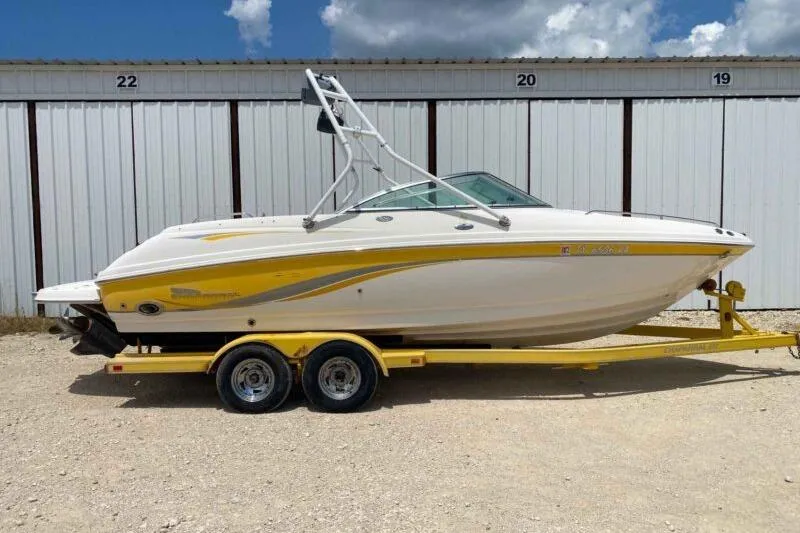 The Image of 2004 Chaparral 230 SSi boat on yellow trailer, parked near storage units. - 1