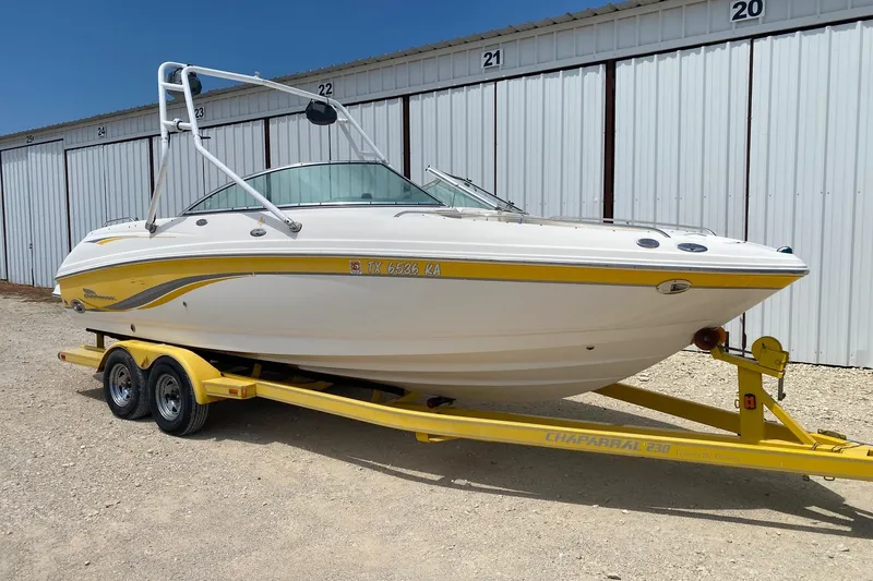 Slide: The Image of 2004 Chaparral 230 SSi boat on yellow trailer, parked near storage units. - 1