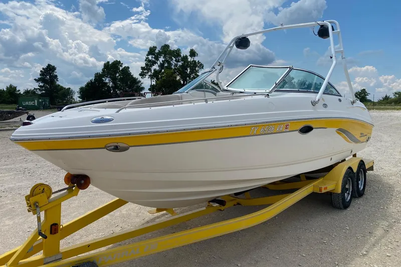 Slide: The Image of 2004 Chaparral 230 SSi boat on trailer, white with yellow accents, parked outdoors. - 2