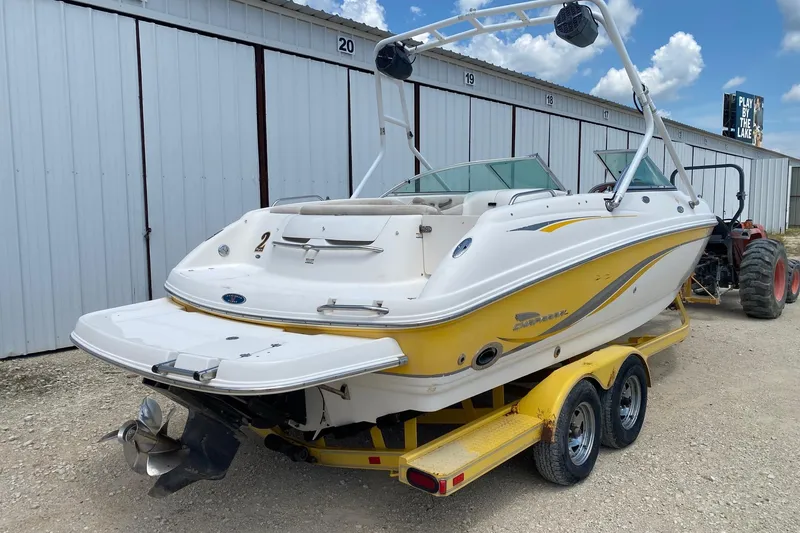 Slide: The Image of 2004 Chaparral 230 SSi boat on trailer, parked near storage units under a blue sky. - 5