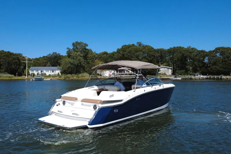 Slide: The Image of 2012 Cobalt 296 boat cruising on a serene lake with lush greenery. - 2