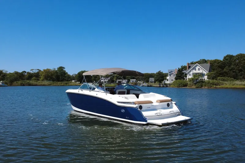 Slide: The Image of 2012 Cobalt 296 boat cruising on a serene lake with houses in the background. - 5