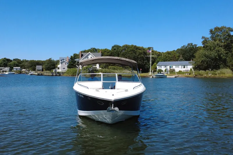 Slide: The Image of 2012 Cobalt 296 boat on calm water near lakeside houses under clear blue sky. - 7