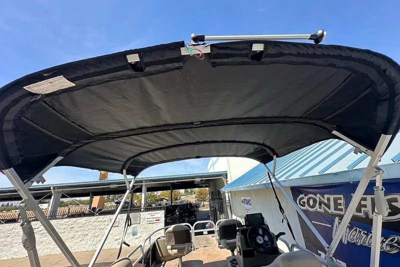 Slide: The Image of 2022 Sun Tracker Bass Buggy 18 DLX with bimini top, docked under clear blue sky. - 34