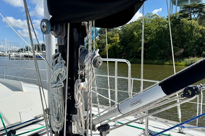 Slide: The Image of Tayana 55 sailboat deck with rigging and ropes, docked by a serene waterfront. - 13