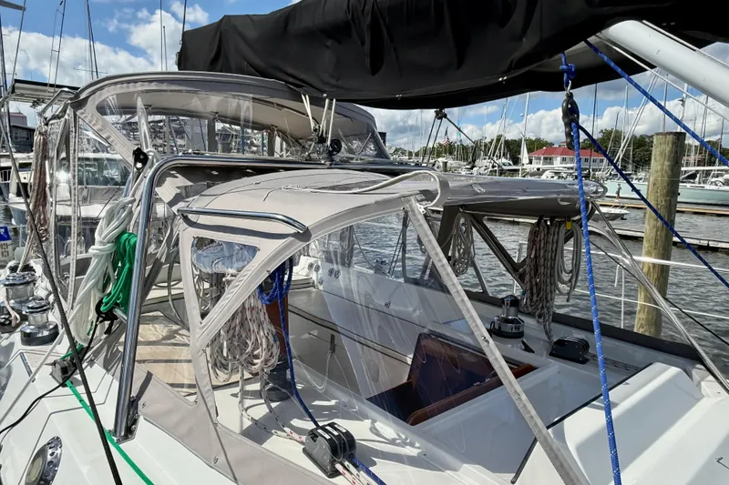 Slide: The Image of 1984 Tayana 55 sailboat with covered cockpit, docked at marina under clear skies. - 15