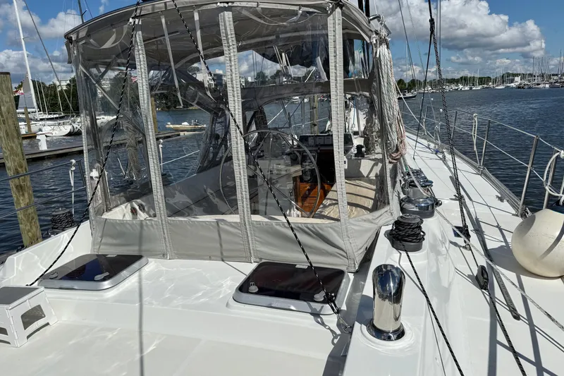 Slide: The Image of 1984 Tayana 55 sailboat with enclosed cockpit, docked at a marina under a blue sky. - 18