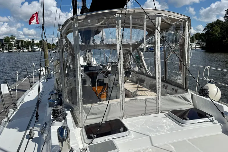 Slide: The Image of 1984 Tayana 55 sailboat with enclosed cockpit, docked by a scenic waterfront. - 19