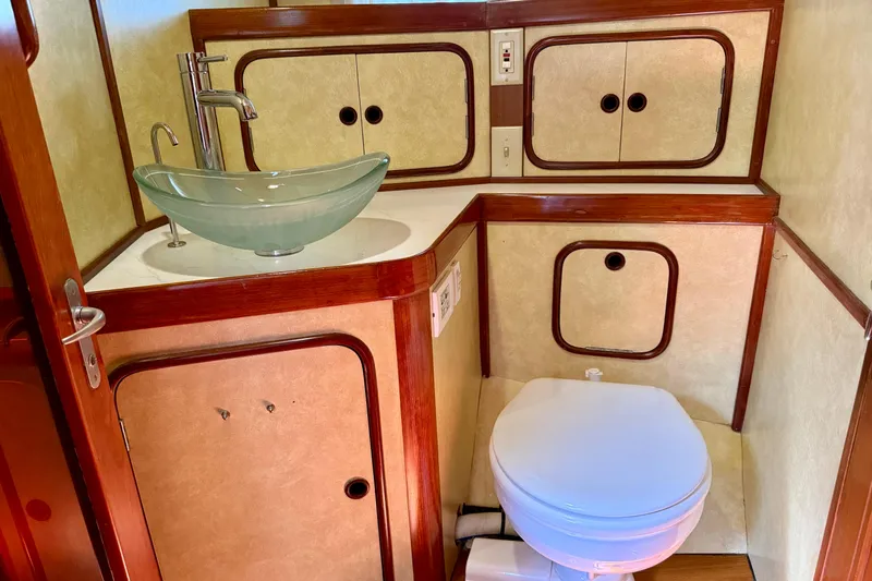 Slide: The Image of Bathroom interior of 1984 Tayana 55 yacht with glass sink and wooden accents. - 32