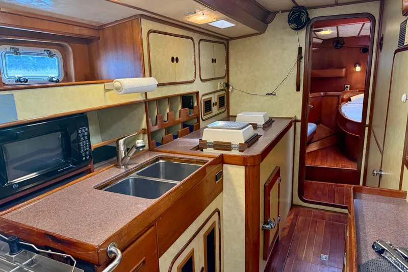 Slide: The Image of Interior of 1984 Tayana 55 yacht featuring a cozy kitchen and wooden cabinetry. - 34