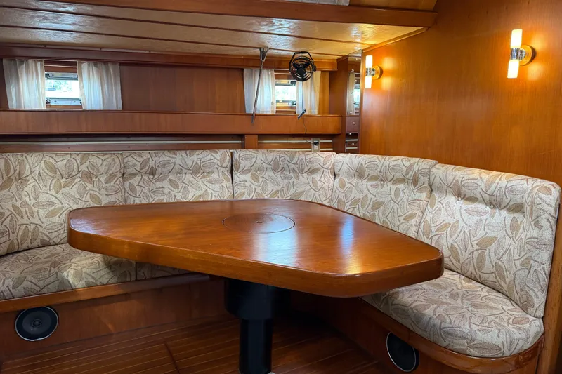 Slide: The Image of Cozy dining area in 1984 Tayana 55 yacht with wooden table and patterned seating. - 36