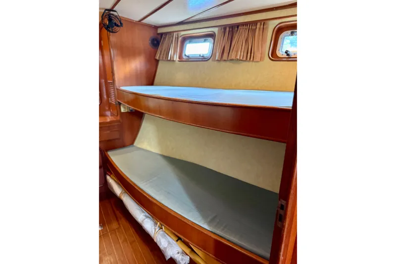Slide: The Image of Interior of 1984 Tayana 55 sailboat featuring wooden bunk beds and porthole windows. - 42