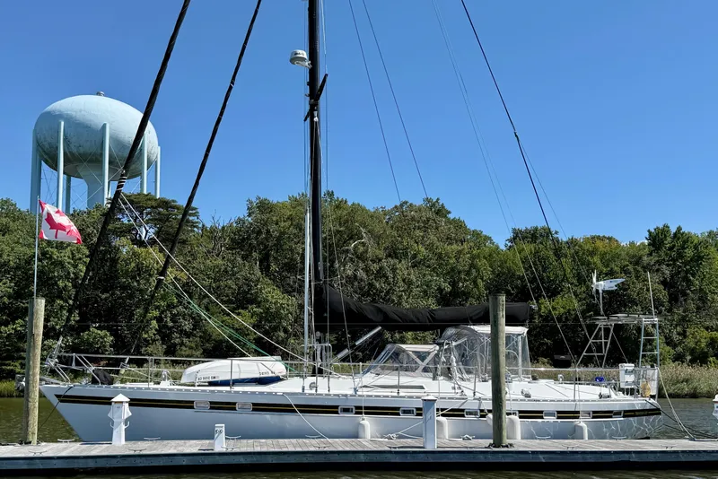Slide: The Image of Sailboat Tayana 55 (1984) docked near water tower, surrounded by trees. - 5