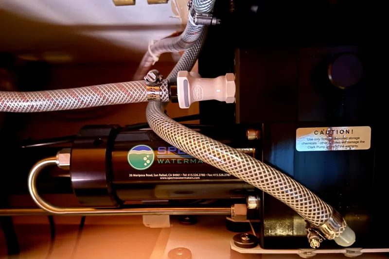 Slide: The Image of Watermaker system in 1984 Tayana 55 yacht, featuring hoses and caution label. - 53