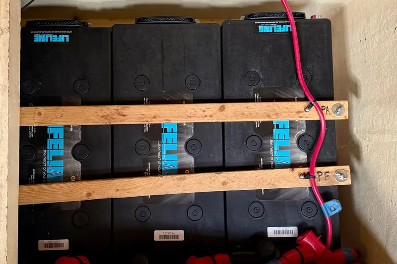 Slide: The Image of Battery compartment of a 1984 Tayana 55 yacht with Lifeline batteries and red wiring. - 57