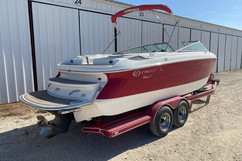 Slide: The Image of Red and white 2004 Crownline 250 CR boat on trailer, parked near storage units. - 9
