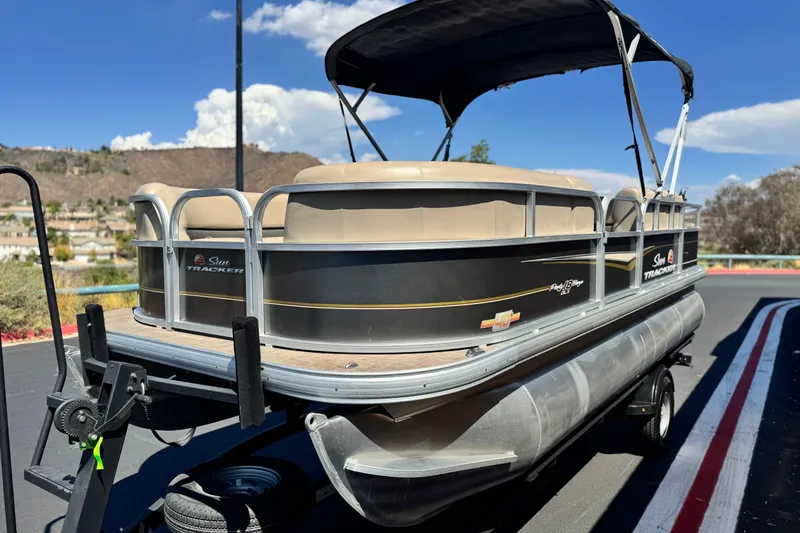 Slide: The Image of 2023 Sun Tracker Party Barge 18 DLX pontoon boat on trailer, scenic background. - 3