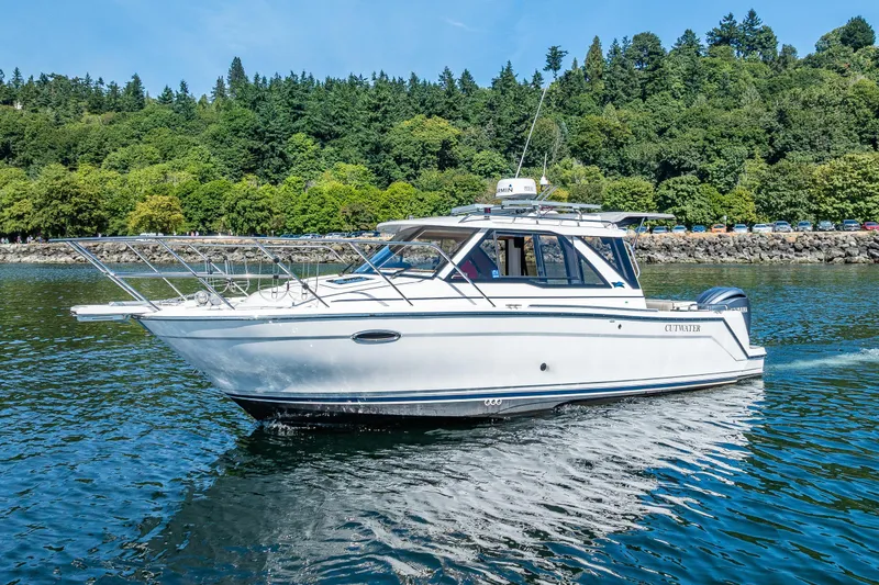 Slide: The Image of 2024 Cutwater C-248 Coupe cruising on a scenic lake with lush green trees. - 2