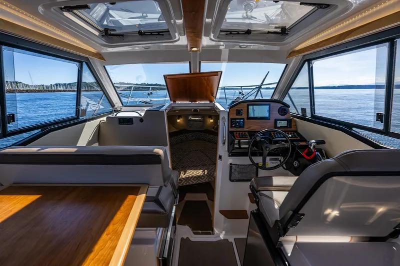 Slide: The Image of 2024 Cutwater C-248 Coupe helm with navigation screens and controls, overlooking rocky shoreline. - 21