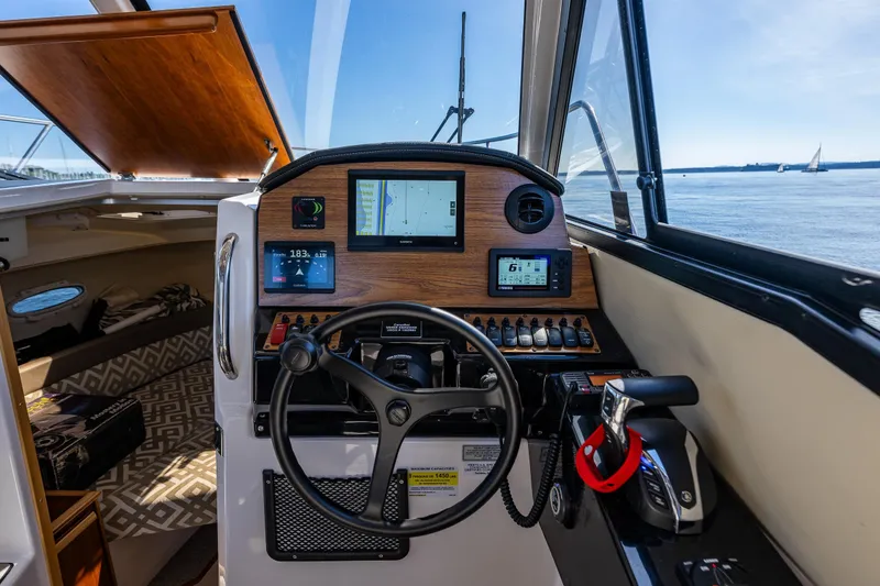 Slide: The Image of 2024 Cutwater C-248 Coupe helm with navigation screens and steering wheel, overlooking serene waters. - 22
