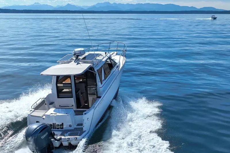 Slide: The Image of 2024 Cutwater C-248 Coupe cruising on open water with scenic mountain backdrop. - 6
