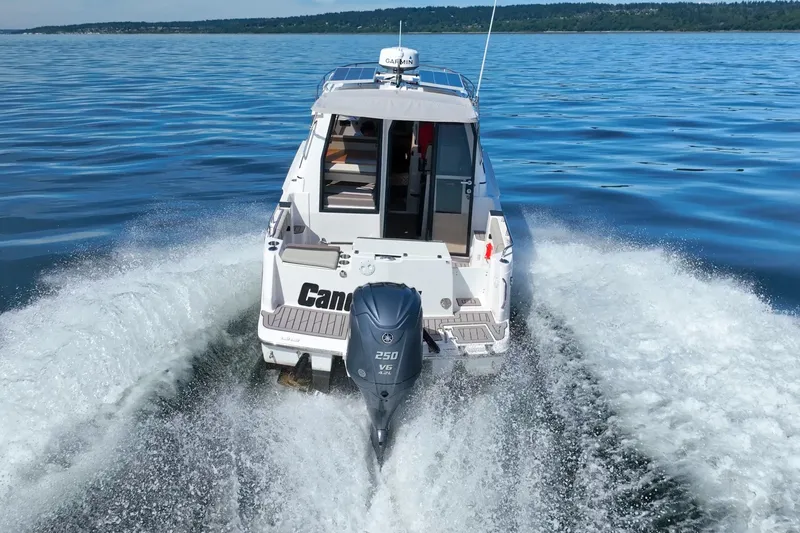 Slide: The Image of 2024 Cutwater C-248 Coupe cruising on a scenic lake with lush green shoreline. - 9