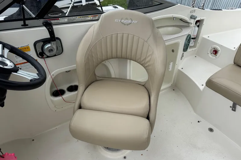 Slide: The Image of 2015 Stingray 215 LR boat interior with beige captain's chair and steering wheel. - 16