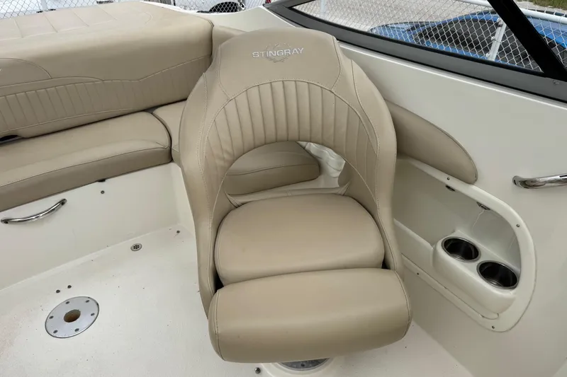 Slide: The Image of 2015 Stingray 215 LR boat interior with beige seating and cup holders. - 17