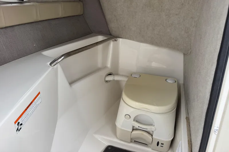 Slide: The Image of Interior of 2015 Stingray 215 LR boat featuring a compact portable toilet. - 20