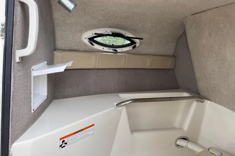 Slide: The Image of Interior cabin of a 2015 Stingray 215 LR boat with porthole and seating. - 21