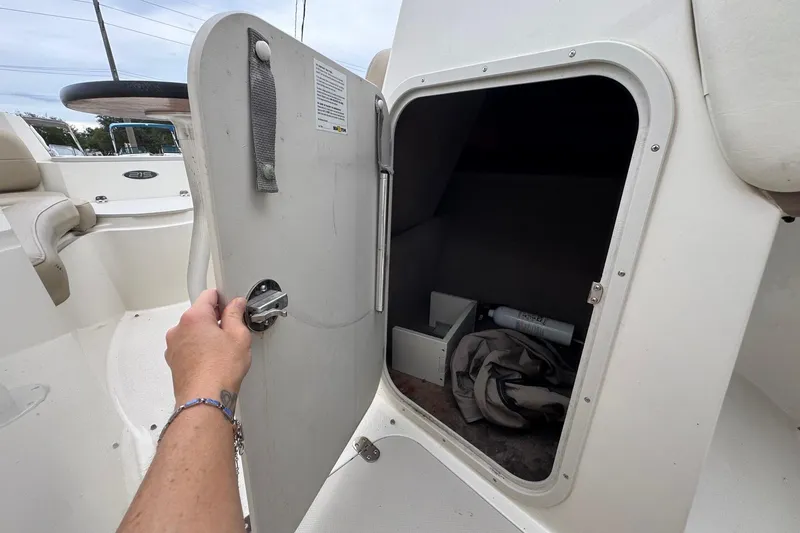 Slide: The Image of 2015 Stingray 215 LR boat storage compartment with open door, revealing interior items. - 24